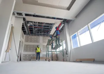 Two people working on an interior ceiling 